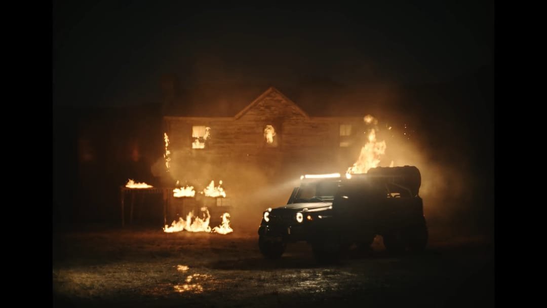 Burning house and a car with headlights at night